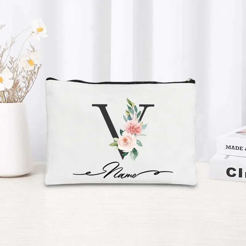 pochette personnalisée en toile noire à motif floral avec initiale en écriture cursive, trousse de toilette fine et compacte pour femmes, idéale pour les voyages et l'usage quotidien.