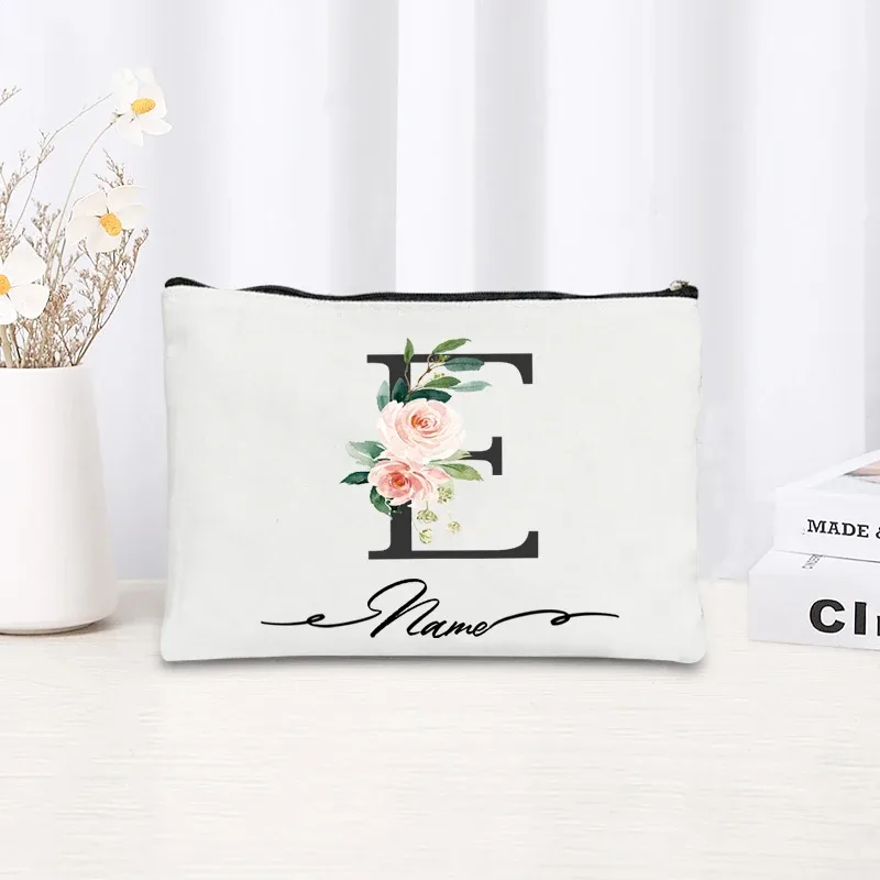 pochette personnalisée en toile noire à motif floral avec initiale en écriture cursive, trousse de toilette fine et compacte pour femmes, idéale pour les voyages et l'usage quotidien.
