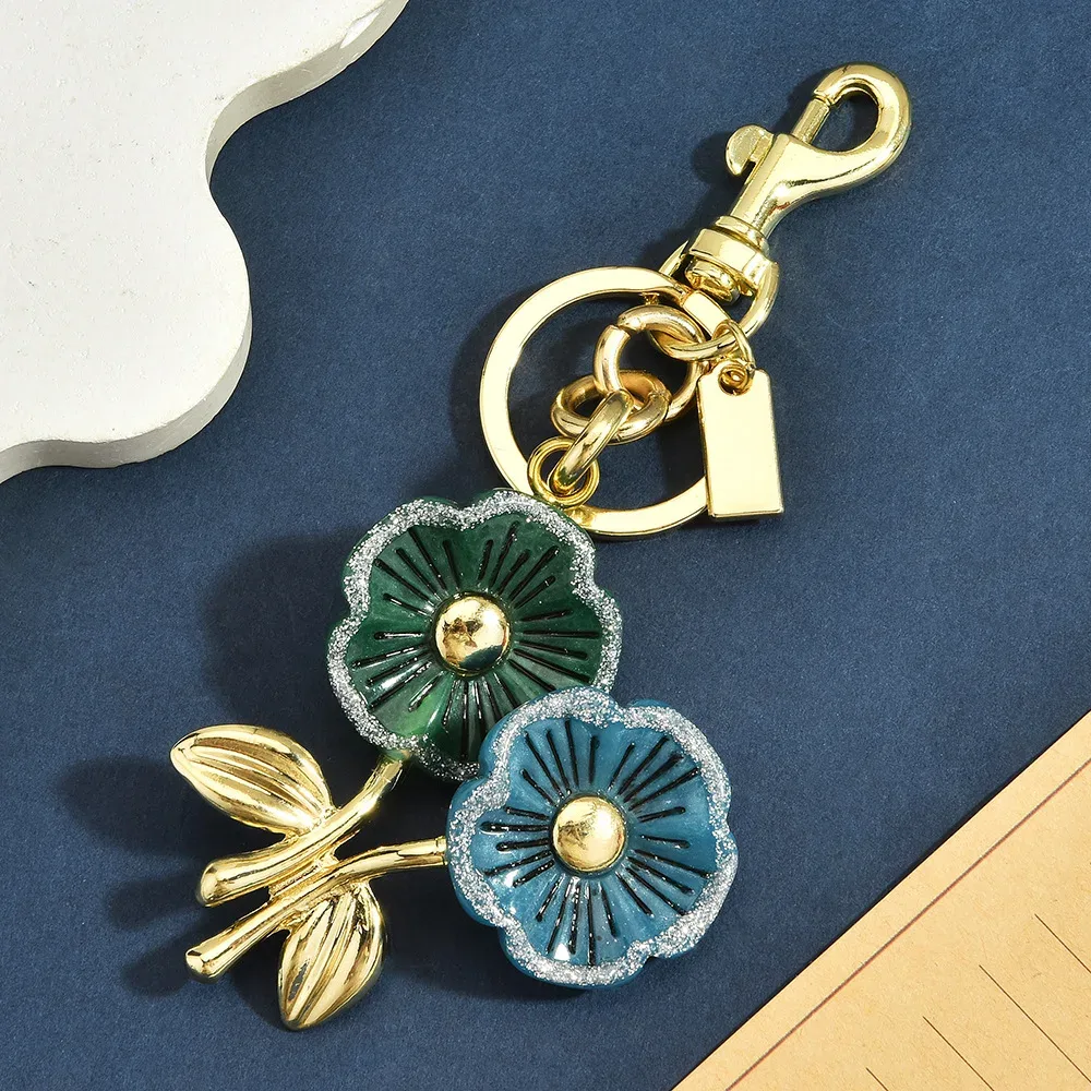 sac dos ornementation fleurs vertes bleues anneau doré pétales brillants feuilles vertes accessoire voyage chic vintage