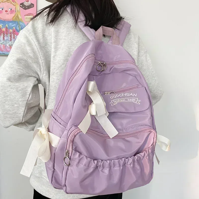 sac dos nylon beige poche ouverte fermeture éclair style preppy arc décoration usage voyage école adolescente femmes