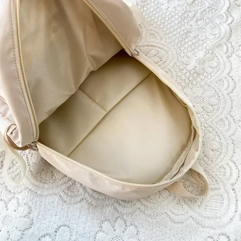 sac dos nylon beige poche ouverte fermeture éclair style preppy arc décoration usage voyage école adolescente femmes