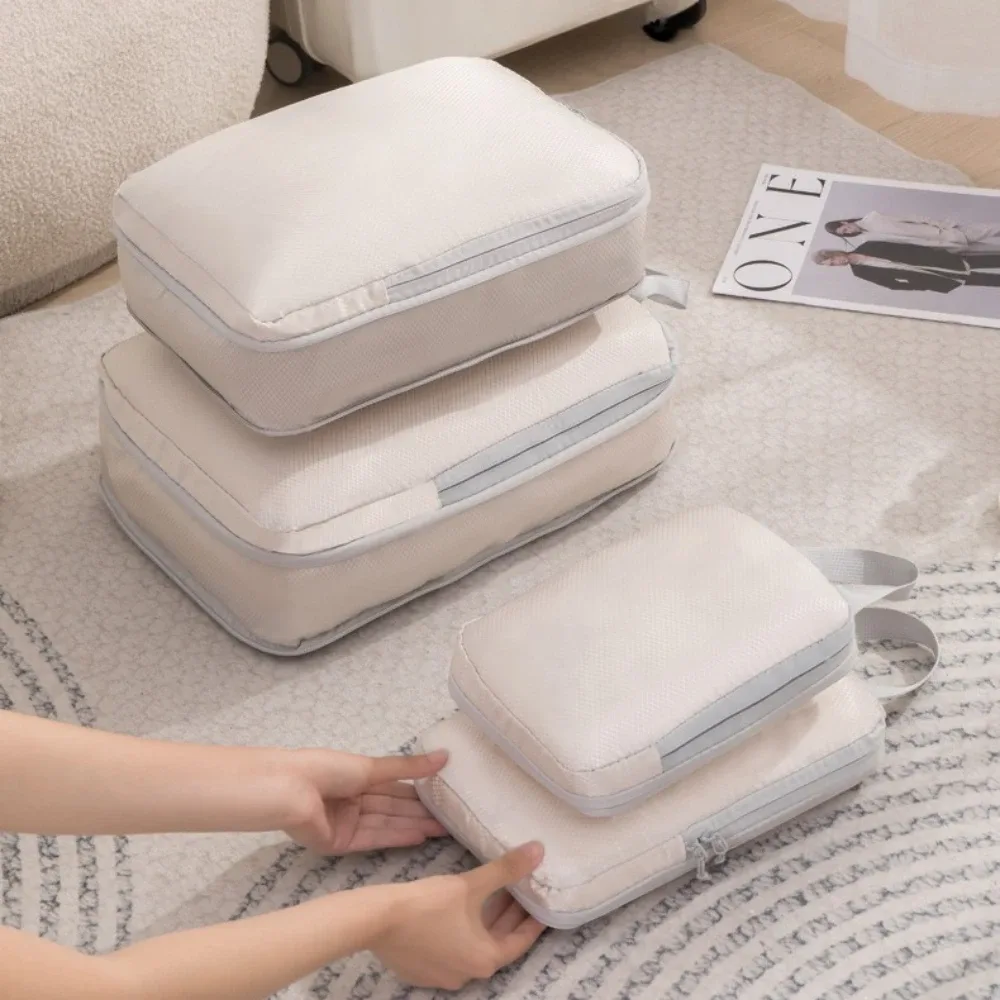 organisateur voyage polyester blanc bandes grises format rectangulaire poignées grises compression vêtements articles toilette rangement valise