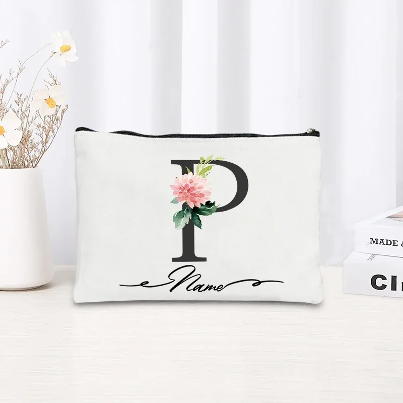 pochette personnalisée en toile noire à motif floral avec initiale en écriture cursive, trousse de toilette fine et compacte pour femmes, idéale pour les voyages et l'usage quotidien.