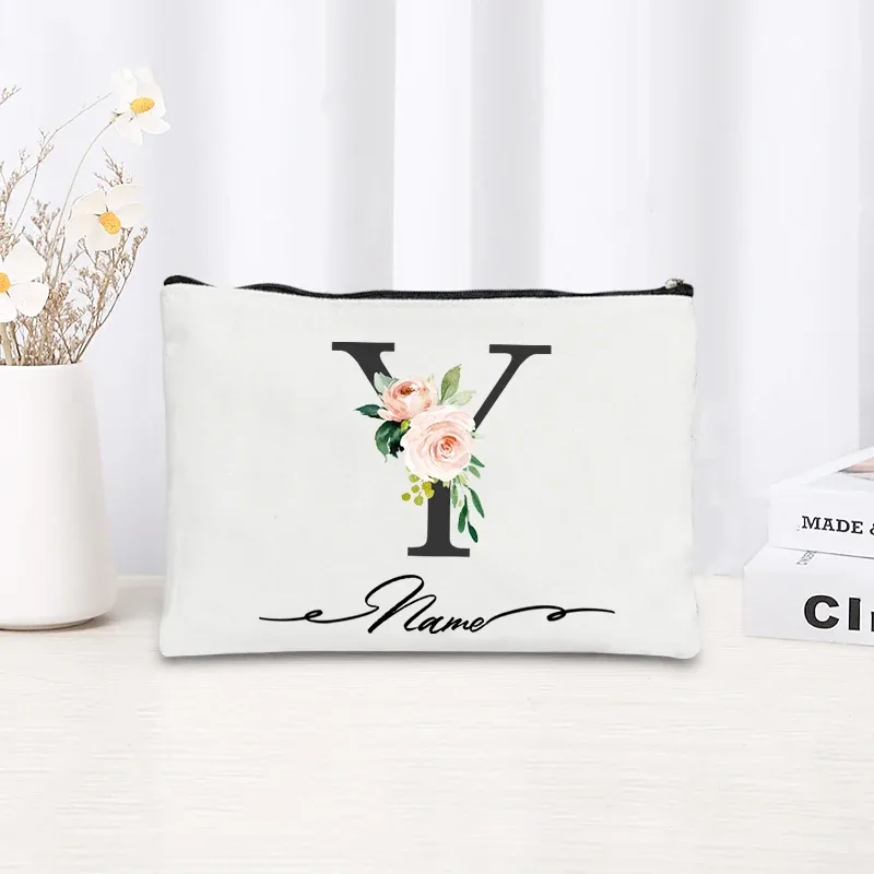pochette personnalisée en toile noire à motif floral avec initiale en écriture cursive, trousse de toilette fine et compacte pour femmes, idéale pour les voyages et l'usage quotidien.