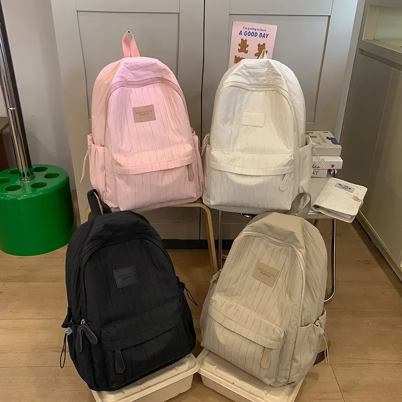 sac dos nylon rose pâle rayures verticales bandes latérales portage poignée supérieure capacité rangement informations voyage