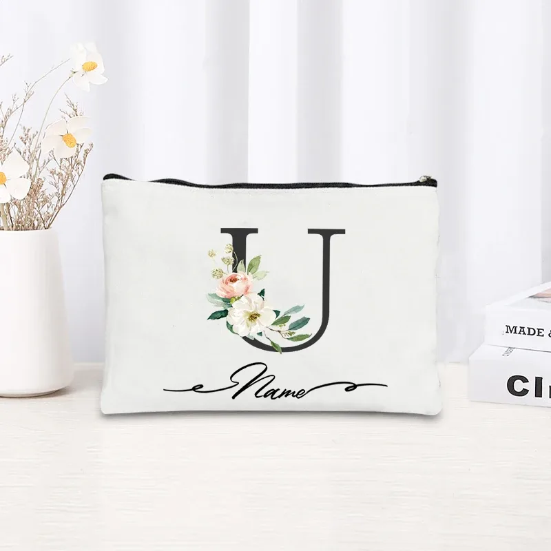 pochette personnalisée en toile noire à motif floral avec initiale en écriture cursive, trousse de toilette fine et compacte pour femmes, idéale pour les voyages et l'usage quotidien.