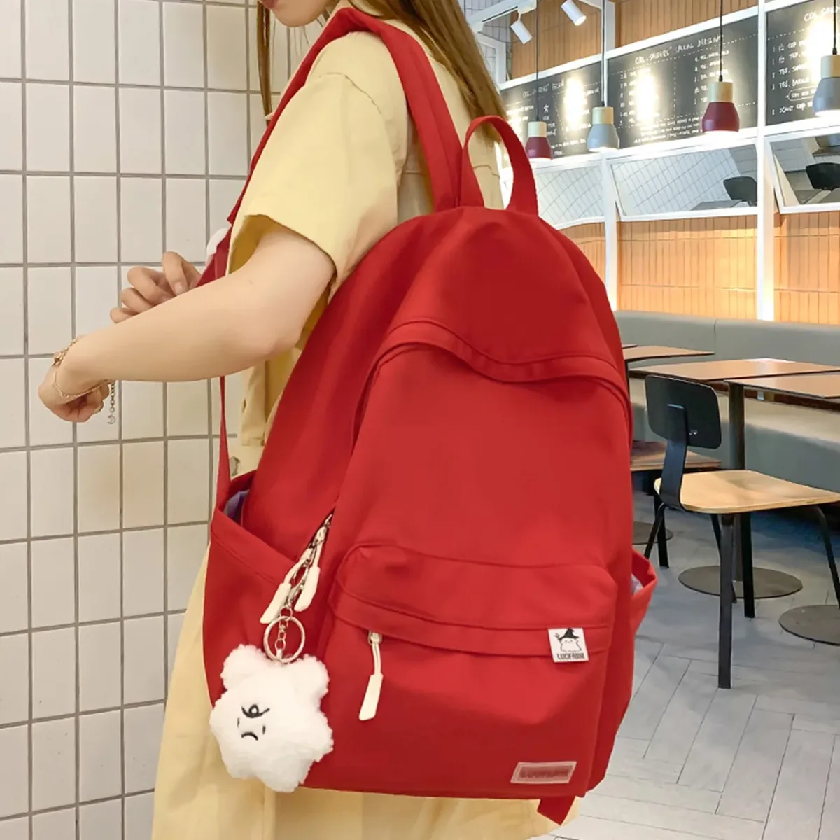 sac dos nylon imperméable vert pastel rouge beige noir poche avant zippée pomponneuse blanche bandoulière arquée usage voyage