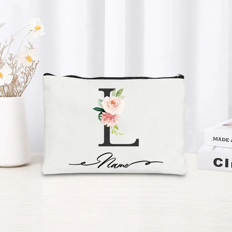 pochette personnalisée en toile noire à motif floral avec initiale en écriture cursive, trousse de toilette fine et compacte pour femmes, idéale pour les voyages et l'usage quotidien.