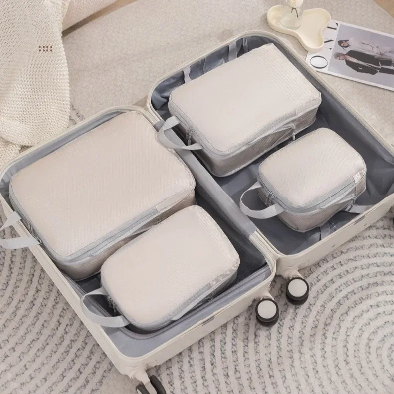 organisateur voyage polyester blanc bandes grises format rectangulaire poignées grises compression vêtements articles toilette rangement valise