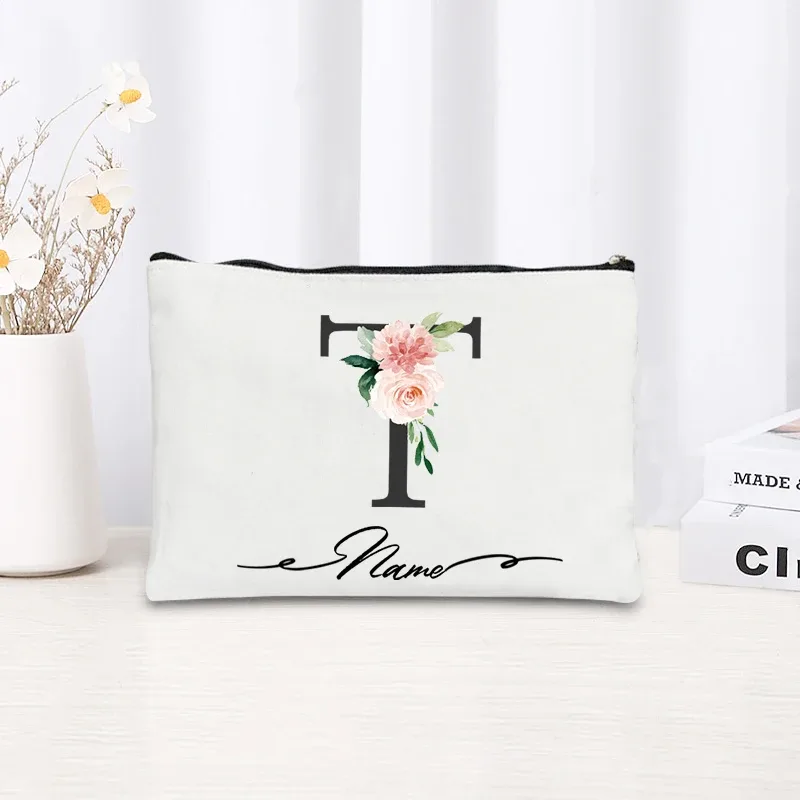 pochette personnalisée en toile noire à motif floral avec initiale en écriture cursive, trousse de toilette fine et compacte pour femmes, idéale pour les voyages et l'usage quotidien.