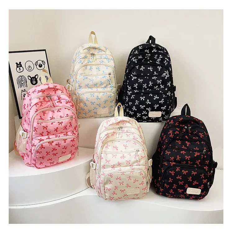 sac dos polyester motifs nœuds rose clair blanc noir bandoulière poignées latérales voyage scolaire femmes