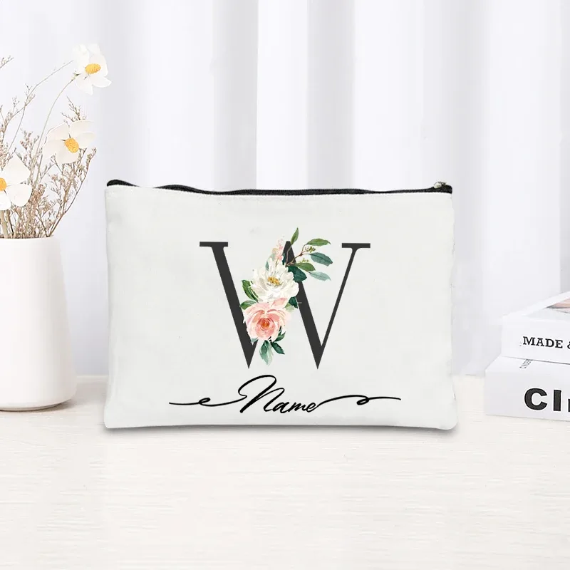 pochette personnalisée en toile noire à motif floral avec initiale en écriture cursive, trousse de toilette fine et compacte pour femmes, idéale pour les voyages et l'usage quotidien.