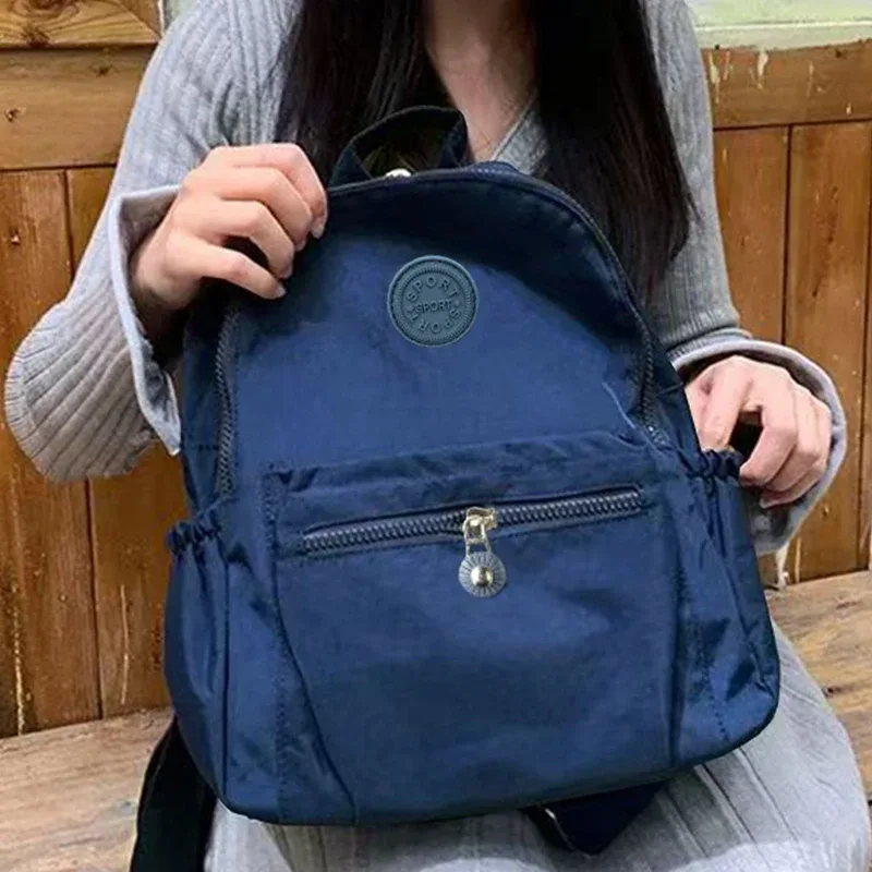 sac à dos multicolore pour femmes avec logo rond, sac à bandoulière tendance pour femmes, disponible en différentes couleurs.