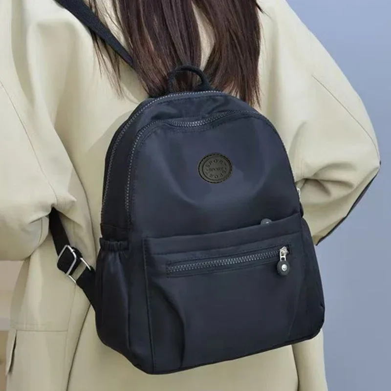 sac à dos multicolore pour femmes avec logo rond, sac à bandoulière tendance pour femmes, disponible en différentes couleurs.