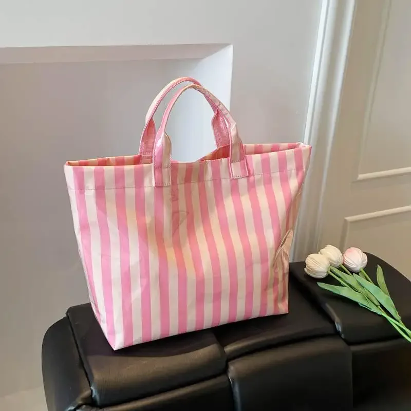 ce sac fourre-tout en pvc résistant à l'eau présente un motif rayé rose et bleu, une grande capacité et convient pour faire du shopping à la plage.