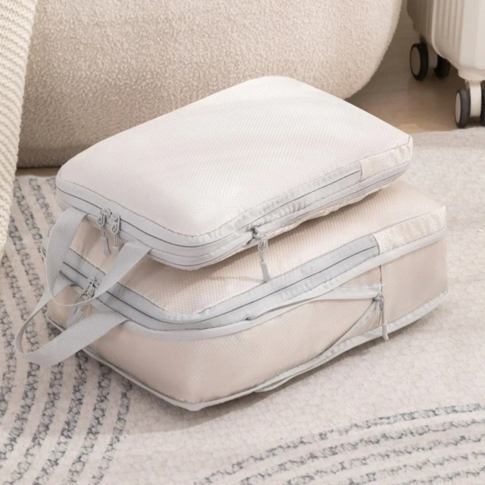 organisateur voyage polyester blanc bandes grises format rectangulaire poignées grises compression vêtements articles toilette rangement valise