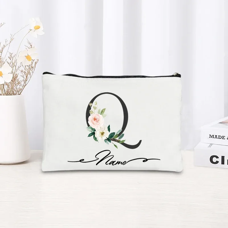 pochette personnalisée en toile noire à motif floral avec initiale en écriture cursive, trousse de toilette fine et compacte pour femmes, idéale pour les voyages et l'usage quotidien.